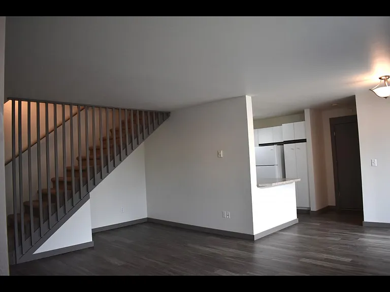 Town home showing a partial view of the living room and dining area and stairs leading upstairs.