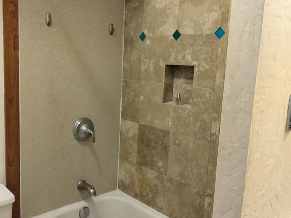 Full bathroom with travertine tile, new toilet. Stocked with 2 sets of towels.