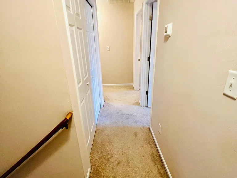 3rd floor hallway with washer/drier on left and two bedrooms to the right