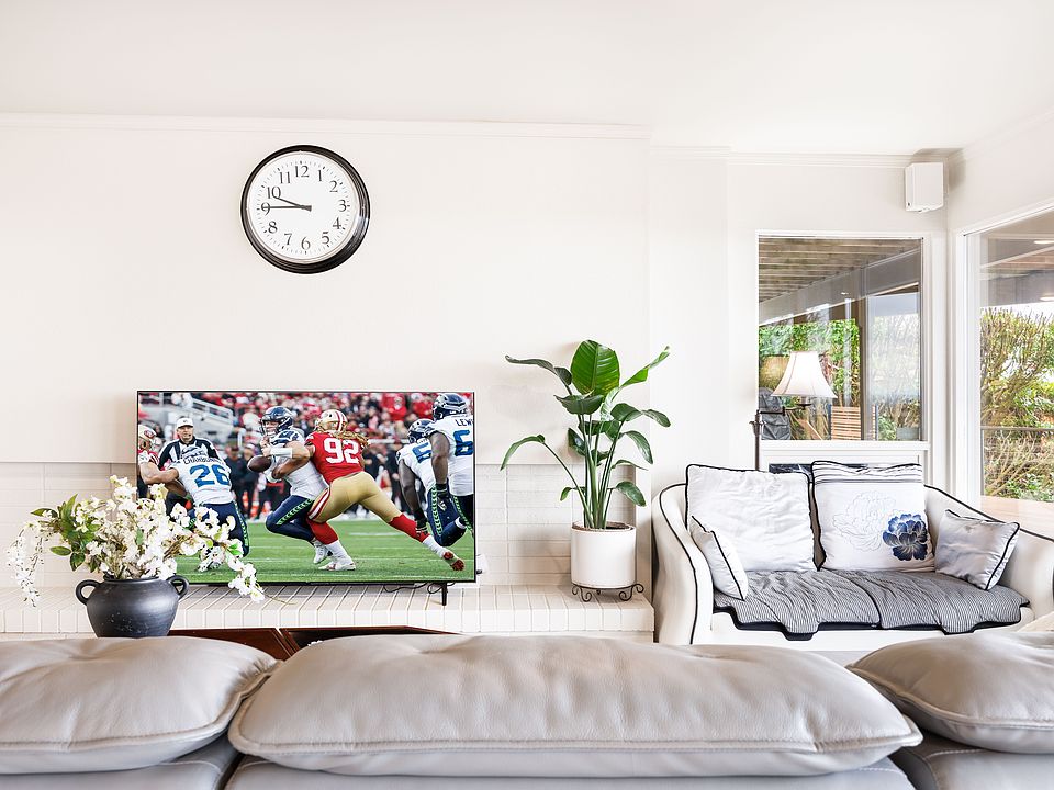 a stylish living area with a large safa,window sofa,green pleant,smart TV. A A perfect space for relaxation with a book or a game night.