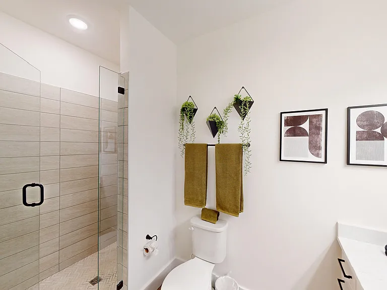 Shower with glass door and tiled wall glass door and white quartz countertops. Nook to put soaps