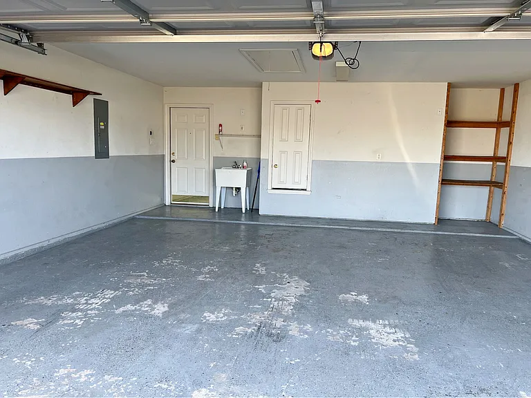 Garage with sink, storage shelves, & attic access.