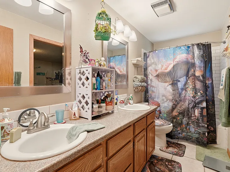 lower level bathroom has twin sinks, tiled backsplash, tiled floor and tiled tub/shower