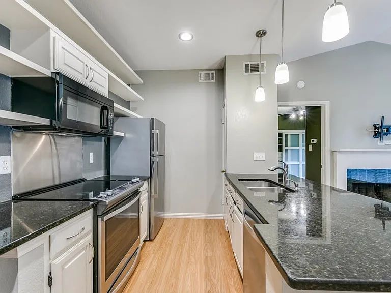 Kitchen featuring sink, dark stone countertops, white cabinetry, and stainless steel appliances