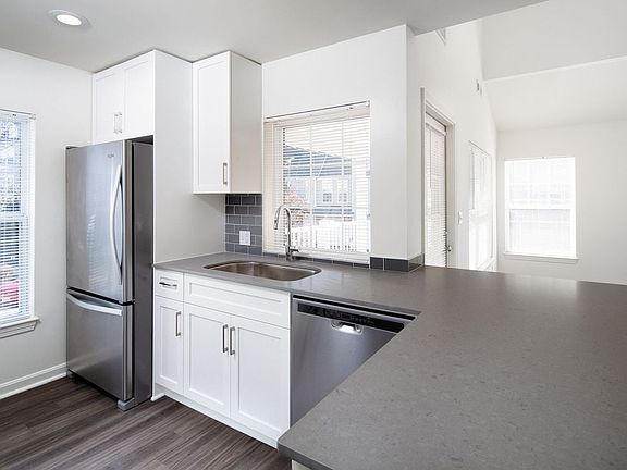 Kitchen with gray quartz countertops, tile backsplash, stainless steel appliances, and upgraded fixtures