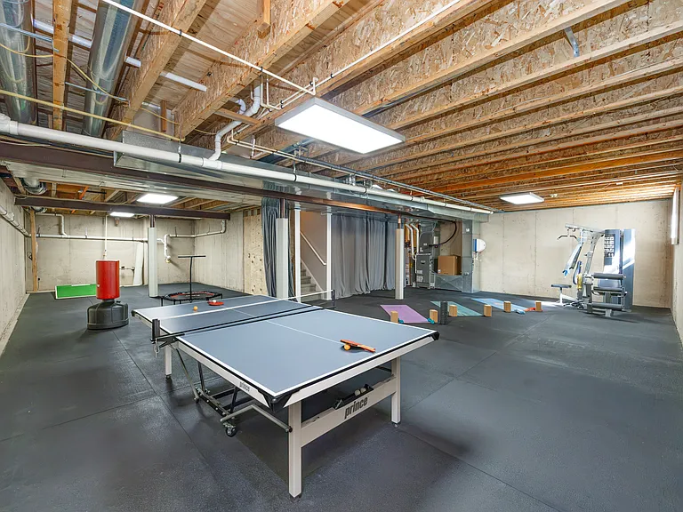 Basement with gym, mounted TV and ping pong