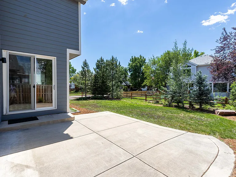 The fully fenced outdoor space offers both a patio and grassy yard, creating distinct areas for entertaining, recreation, and relaxation.