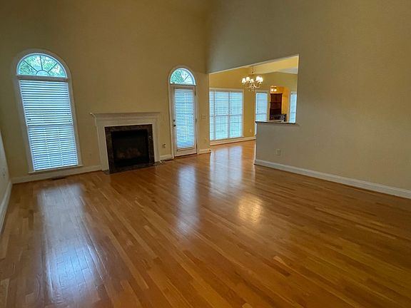 Living room with hardwood floors, volume ceiling, and gas log fireplace