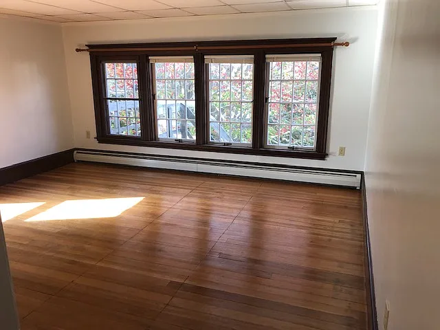 Living Area With Beautiful Floor To Ceiling Windows, And Hardwood Flooring.
