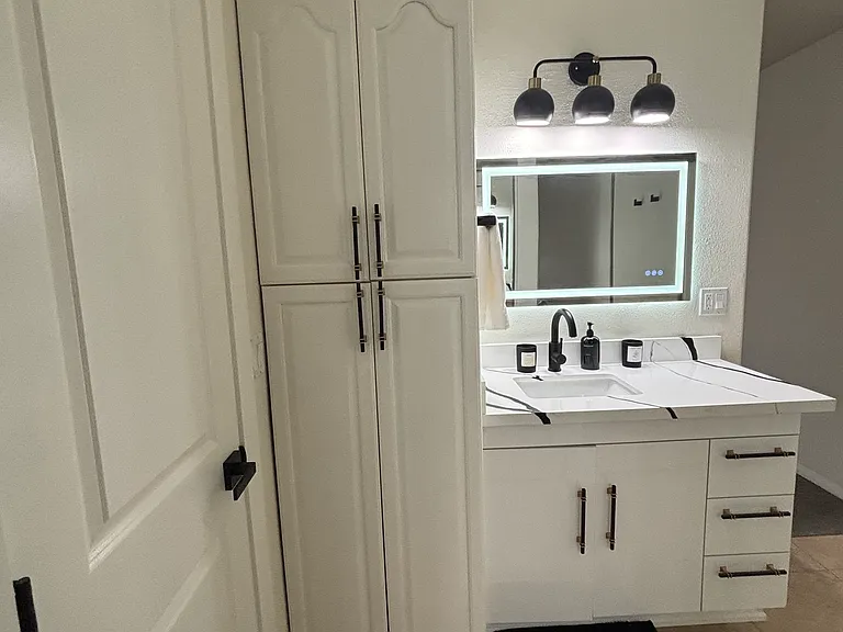 Upstairs Primary sink with lighted mirror, & linen storage