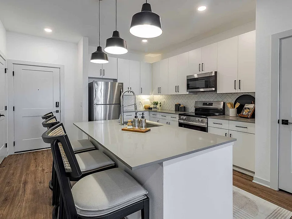 A bright, modern kitchen welcomes you home, complete with crisp white cabinetry, stainless steel appliances, and an island made for casual dining.