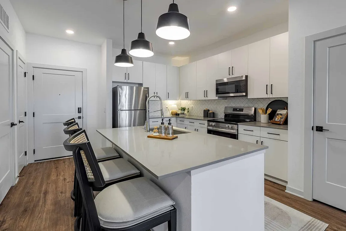 A bright, modern kitchen welcomes you home, complete with crisp white cabinetry, stainless steel appliances, and an island made for casual dining.