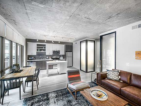 Open concept kitchen and living areas with hard surface flooring and floor to ceiling windows