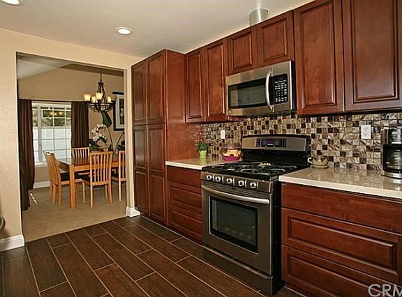 Newly remodeled kitchen with marble countertops, glass tile backsplash, stainless steel appliances, new tile flooring that looks like wood