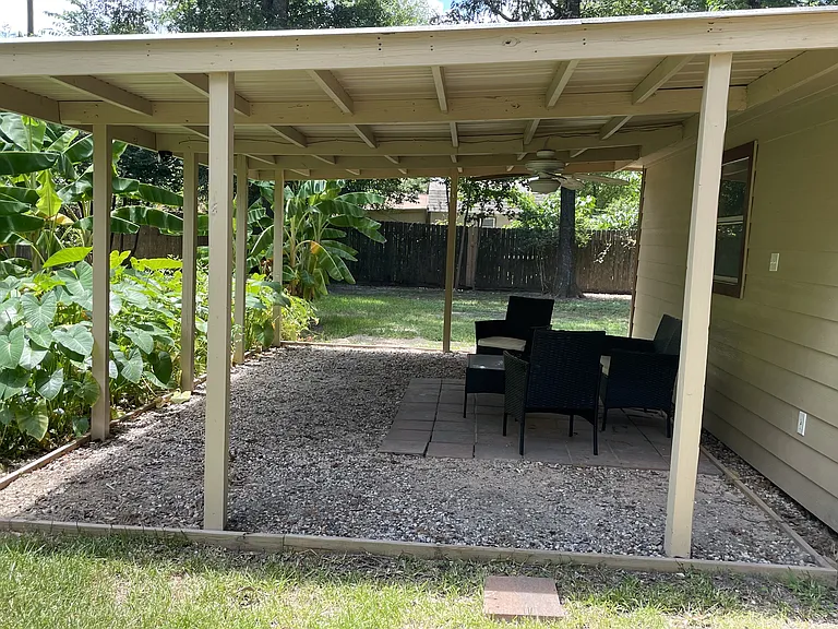Patio overlooking back yard with fan, lights, electrical outlets and furniture.