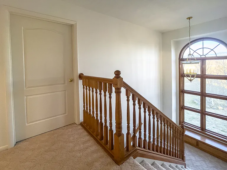 Oak railings line the stairway to upper floor, and this large arched window brings in light to the space.