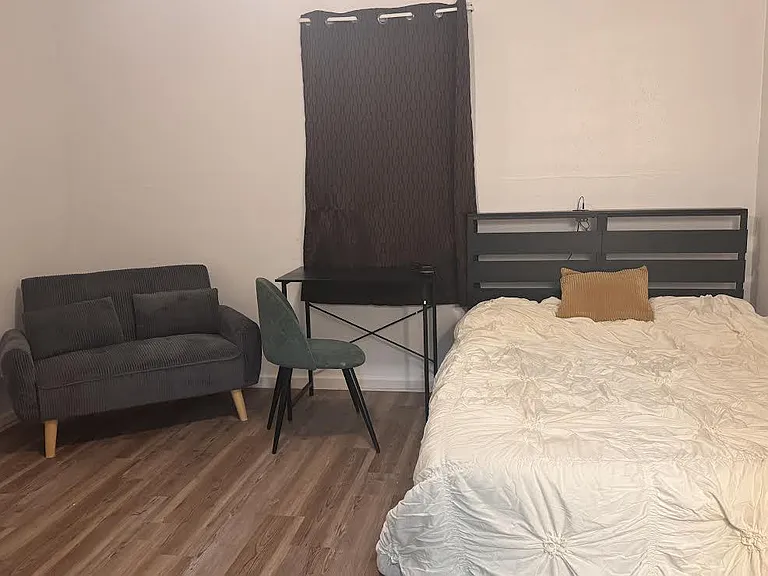 Furnished featuring a full bed, dedicated desk workspace, and loveseat, with durable wood-look flooring.