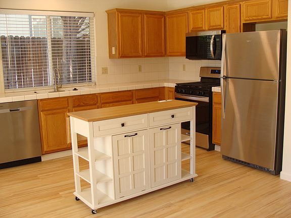 Kitchen with New Stainless Steel Appliances with Convenient Moveable Island is Open Concept with Family Room with Gas Fireplace, and looks out to Canyon View Backyard