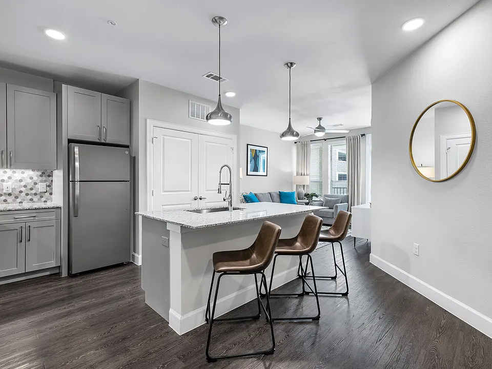 Kitchen with granite island and stainless appliances open to a bright living room