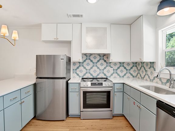 Kitchen with custom tile backsplash, custom hood, new appliances and luxury lighting