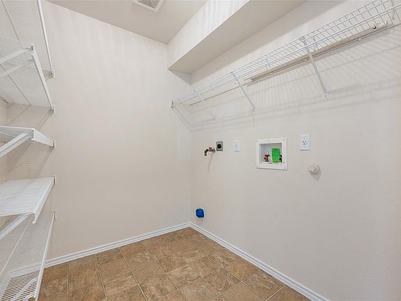 Large pantry off kitchen with shelving and washer/dryer hookup. Across the way is a half bath