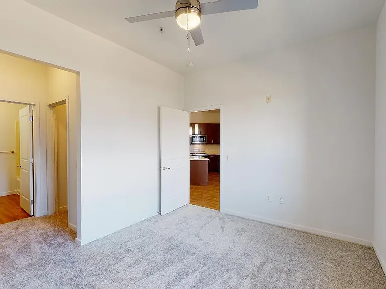 Spacious apartment bedroom with large closet and plush carpet flooring.