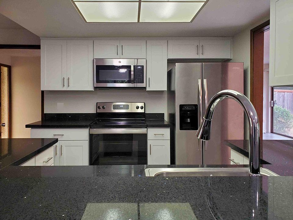 Remodeled kitchen with white quiet close cabinets, black quartz countertop and stainless steel appliances.