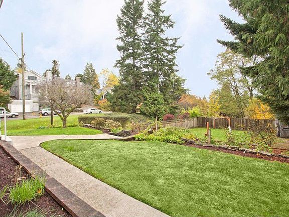 This view, taken from the part of the lot that is across the street, shows the house and terraced yard, which extends west past the left edge of the photo.