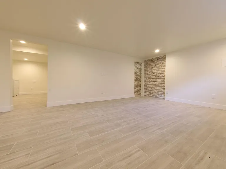 Basement Living area looking towards Laundry. Wood look tile floors and recessed lighting