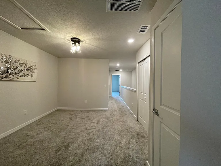 Loft area and hallway to primary bedroom adjacent to stairwell