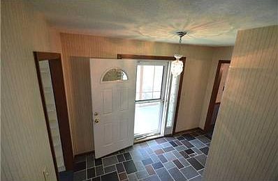 Entry. Bright entry with sidelights on both sides of front door and stone floors in good condition
