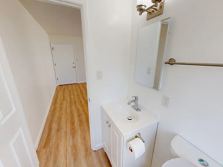 Bright, modern bathroom with sleek vanity, large mirror, and wood-style flooring. Bright, modern bathroom with sleek vanity, large mirror, and wood-style flooring.