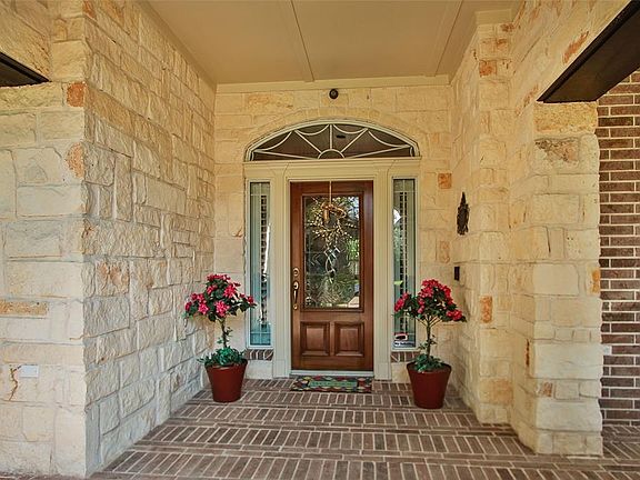 Stunning stone accents the walls and also offers brick paver porch. Sidelights and transom window above mahogany door with Ring doorbell for added security.