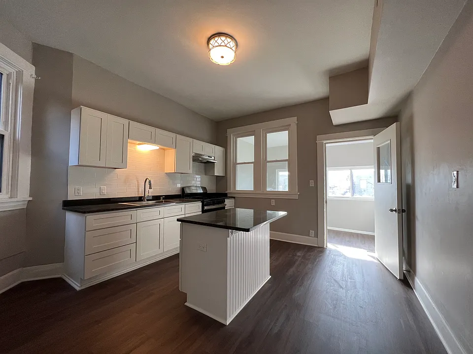 Newly renovated kitchen with granite countertops, crisp white cabinets, brand new stainless steel appliances, food pantry, and island which opens up to the den space.