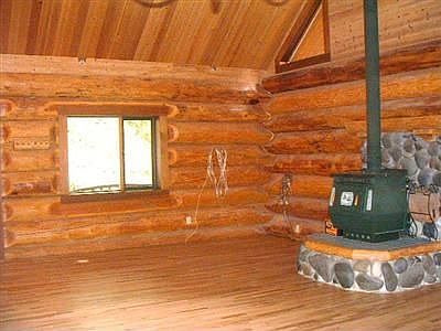 Large living room with 22ft tall ceilings, gleaming hardwood floors and a wood burning stove to keep