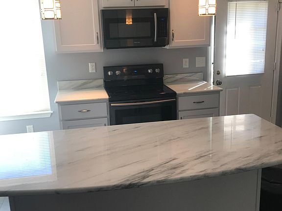 Samsung microwave and electric stove with large island underneath cabinets seats 5.