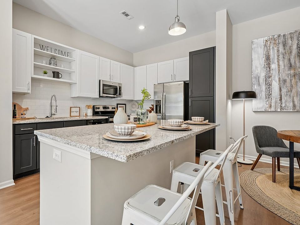 Kitchen with white and dark cabinetry, speckled granite countertops, white subway tile backsplash, stainless steel appliances, and hard surface flooring