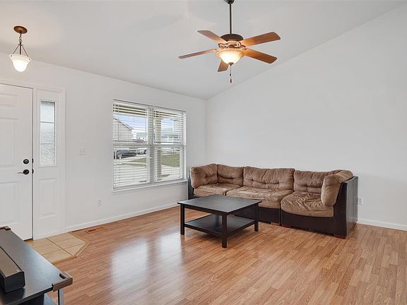 Vaulted great room with wood laminate flooring is open to kitchen.