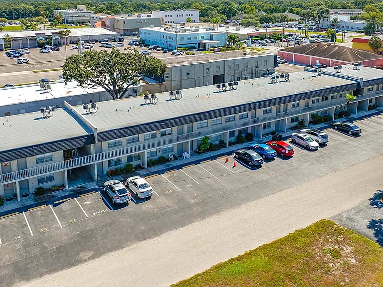Charming apartment complex with ample parking, nestled in a vibrant community setting surrounded by lush greenery.