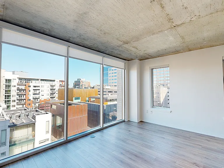 Apartment living room with wood-style flooring and floor-to-ceiling windows.