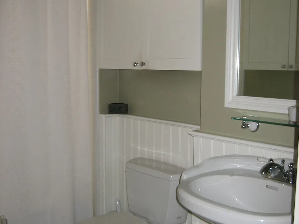 Main bathroom with marble flooring, wainscot paneling, much storage