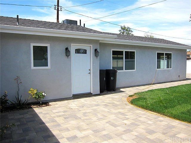 Front of the house with small grass area patio, and paved wa