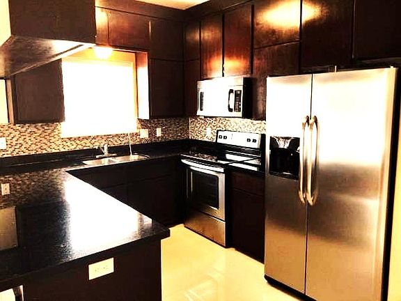 Clean Kitchen with Black quartz Counter Tops, Refrigerator, Stove and Microwave. Open to Dining and Living areas
