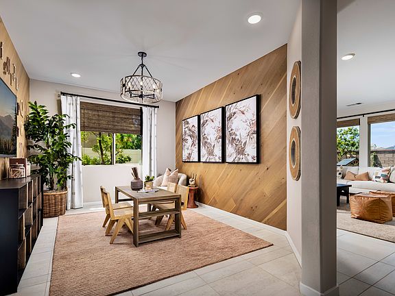 A cozy and inviting dining area with wooden paneled walls, a rustic chandelier, and a wooden table s