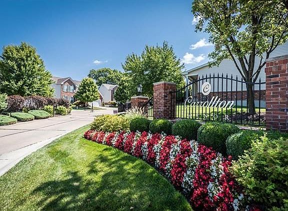Beautifully manicured landscaping at front entrance with security gate/code in the distance.