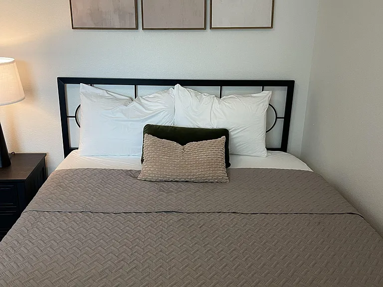 Comfortable bedroom with a metal bed frame, nightstand and lamp, plus wall art and neutral finishes for easy furnishing.