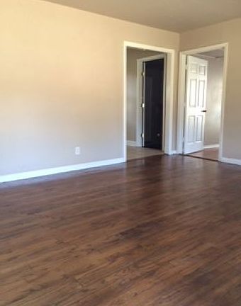 living room with kitchen to left and third bedroom to right