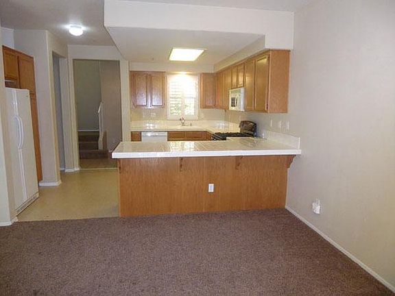 Kitchen and breakfast bar looking from dining room toward entry and staircase.