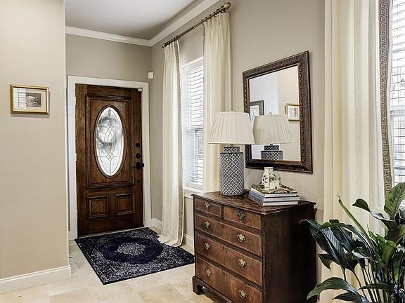 Warm entry area with beautifully stained door, windows that look out to the front yard, faux wood blinds, crown molding and more.