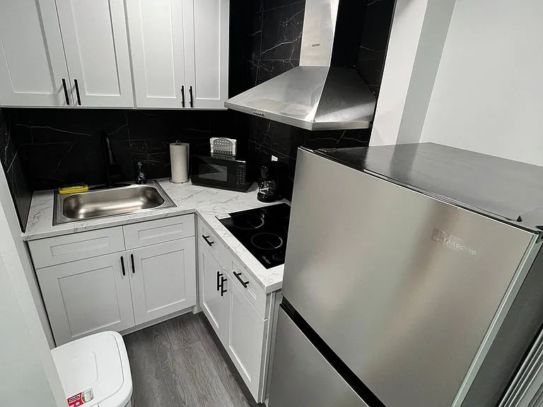 Fully equipped kitchen with drawers, sink, fridge, microwave, coffee maker and stove.